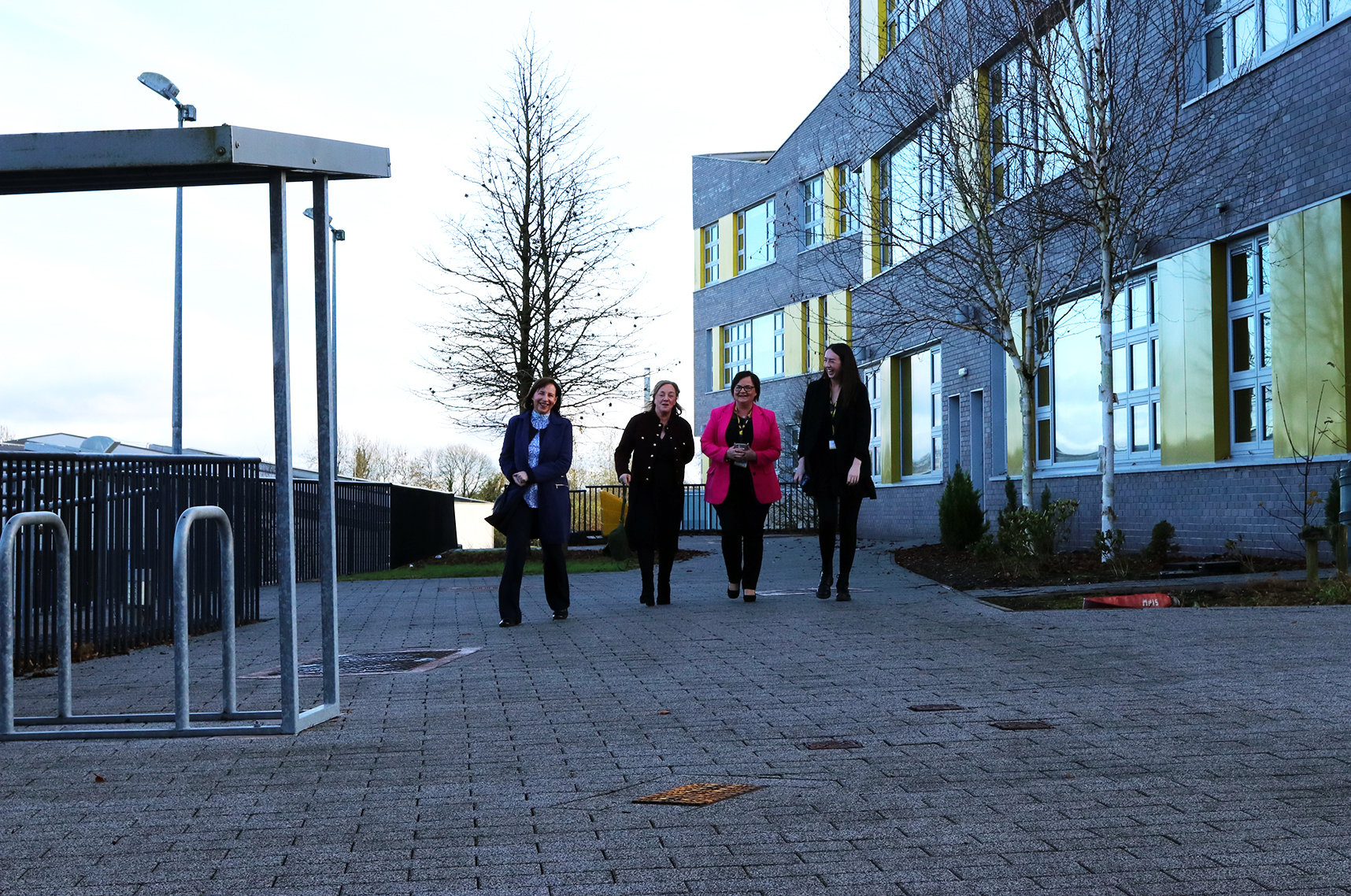 Four staff members walking outside Monaghan Institute building smiling