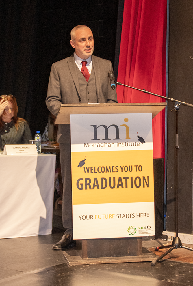 Man talking into microphone at graduation