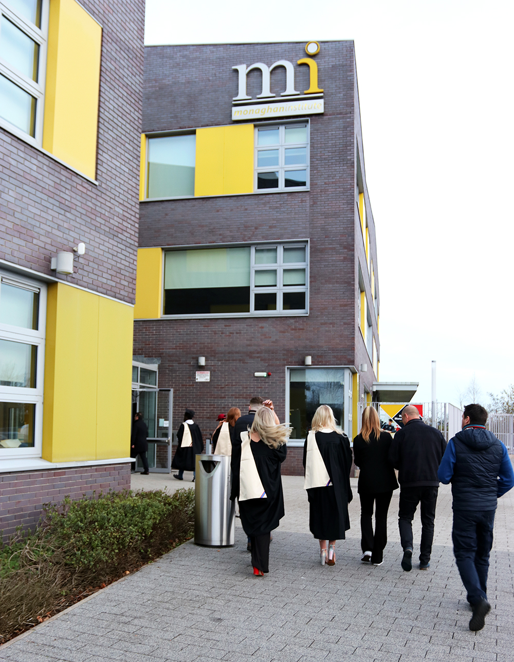 Graduation students walking into Monaghan Institute Building