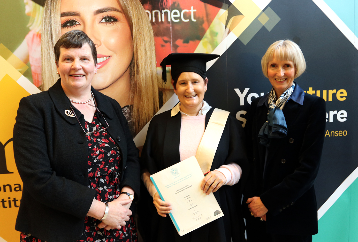 Student graduating holding cert with two women