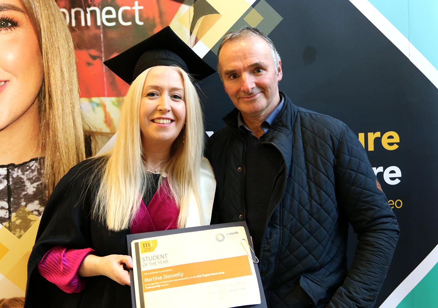 Woman graduating holding student of the year cert with a member of family