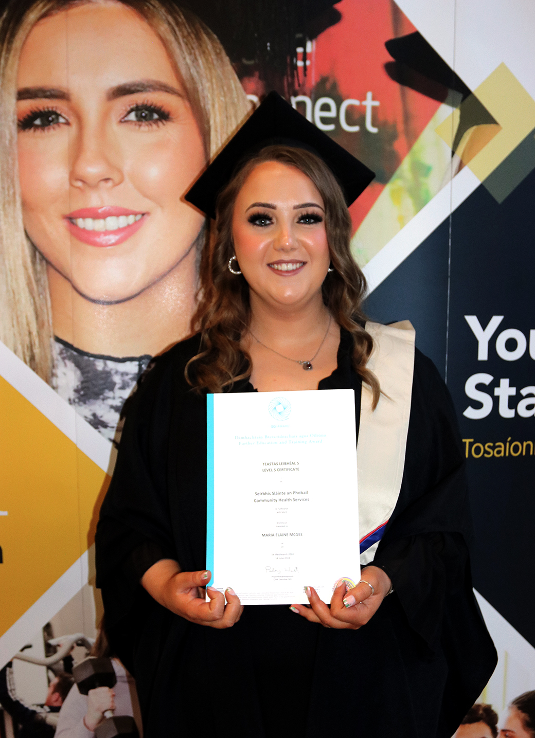 Student smiling with cap and gown holding certificate
