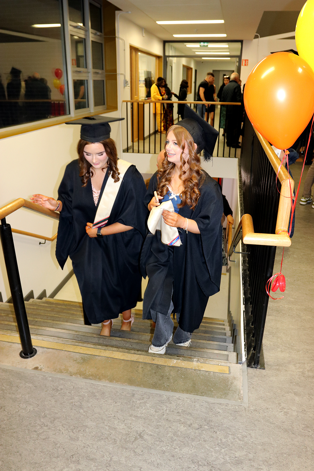 Two girls walking upstairs with cap and gowns on