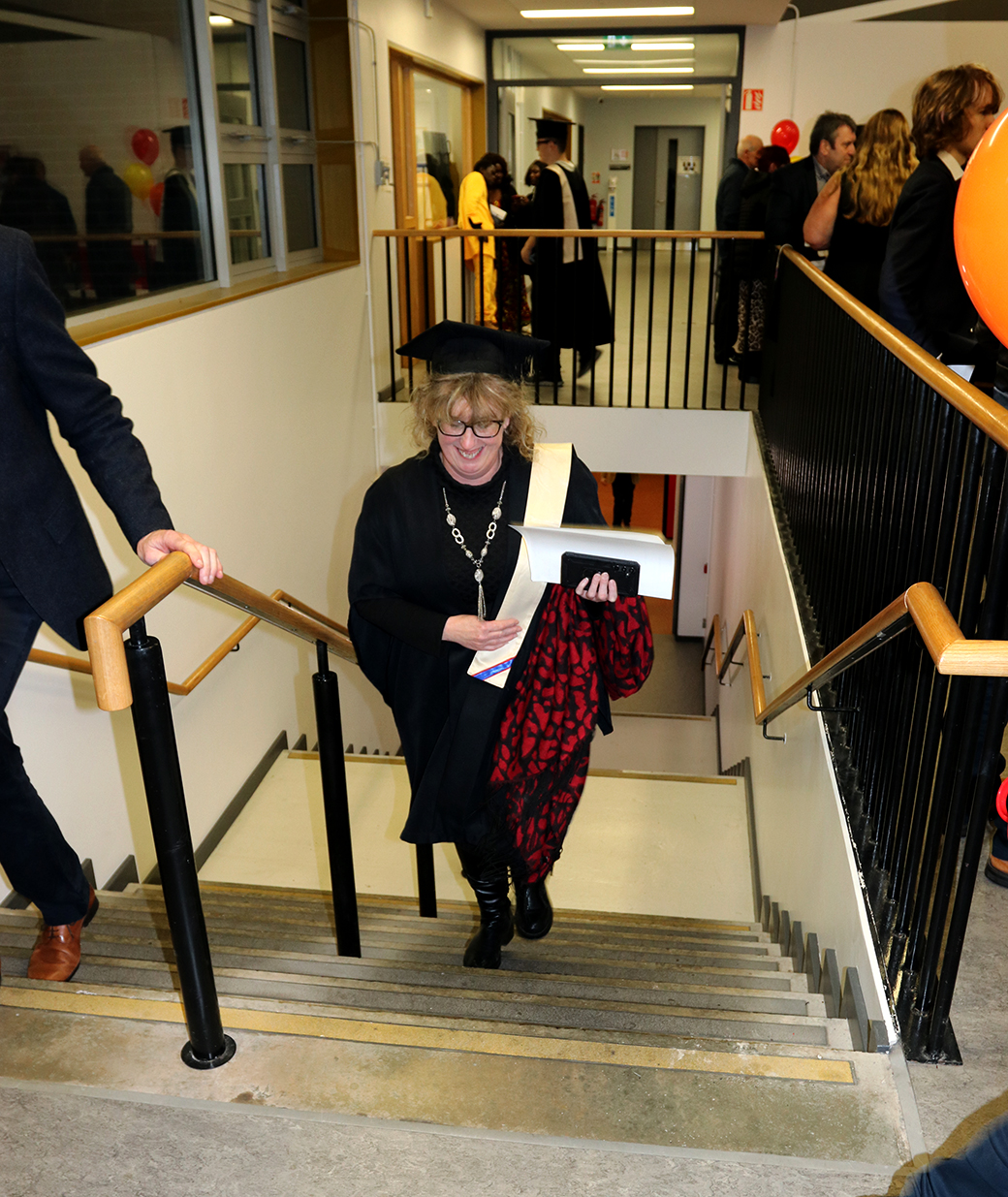 Woman walking up stairs with cap and gown on
