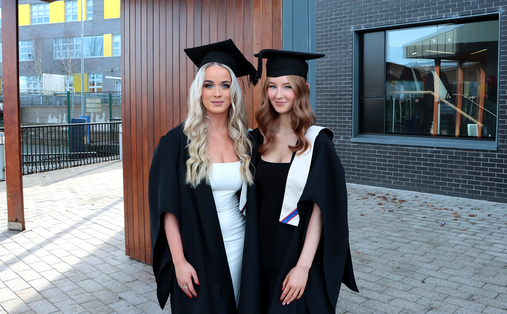 Two students standing with cap and gowns