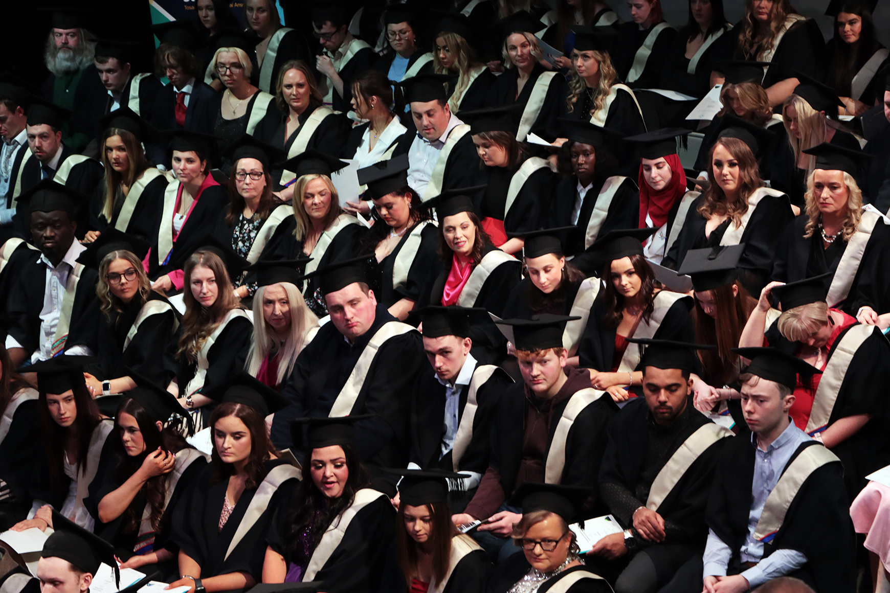 Graduation students sitting with cap and gowns
